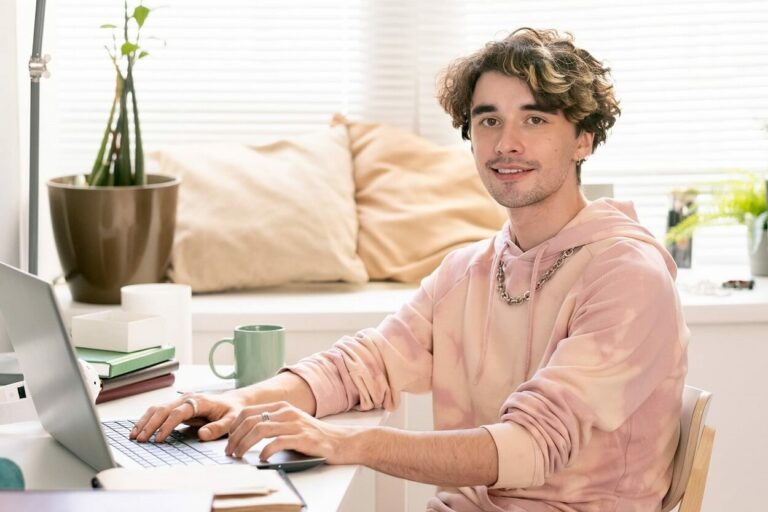 Junger Mann arbeitet mit Laptop und trinkt Kaffee vom Arbeitszimmer